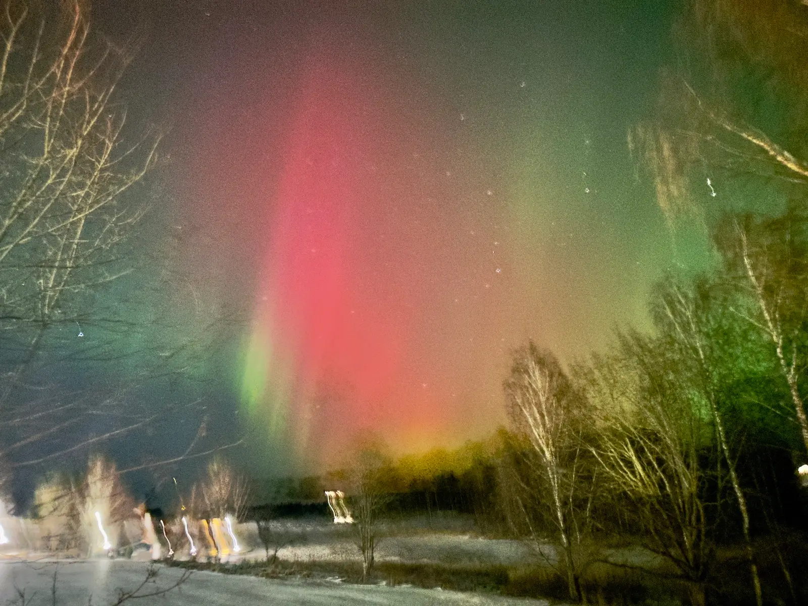 Red green aurora borealis pillars blazing over frozen Finnish lake Ruka