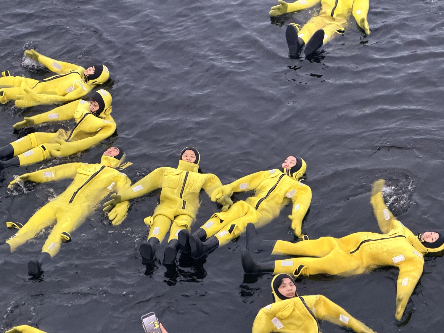 Guests floating in thermal survival suits in the Arctic sea
